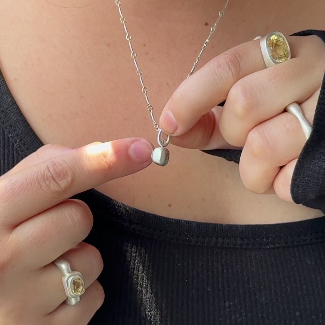 Handmade two sided sterling silver spinner pendant with a natural yellow sapphire and recycled diamond hung on silver bar chain by em jono 